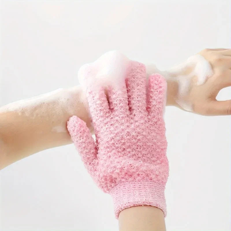 A hand wearing a pink exfoliating shower glove with white foam on the skin.
