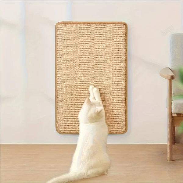 A white cat is using a beige sisal scratch pad to scratch against a wall.