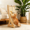 Un gato naranja esponjoso está relajándose en un rascador vertical de sisal natural en interiores.