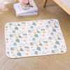 A white pet cooling mat featuring a pattern of dinosaurs and flowers on a light background.