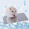 A fluffy white hamster is resting on a silver aluminum cooling pad with ice snowflake graphics.