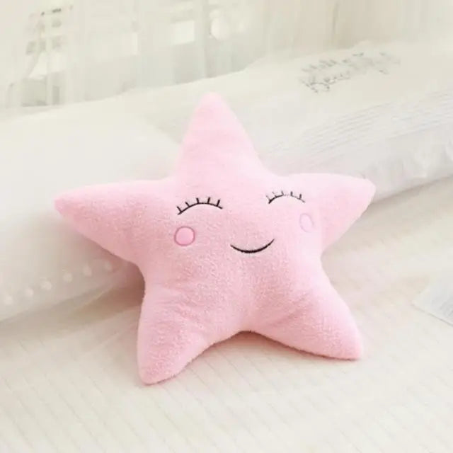 A pink star-shaped plush pillow resting on white bedding.