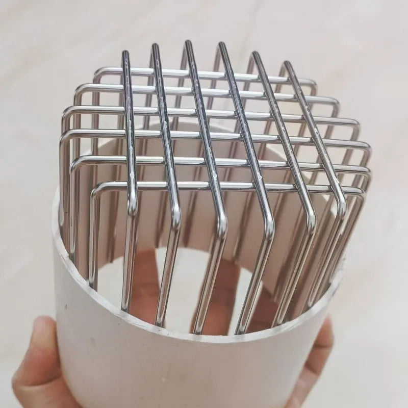 A hand holds a stainless steel roof and floor drain mesh cover with parallel vertical slats.