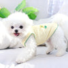 Un perro blanco esponjoso con un collar de peluche fino amarillo claro, tumbado sobre una superficie blanca.
