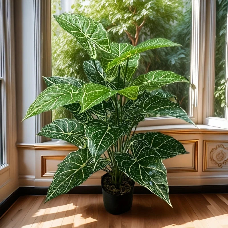 A large artificial monstera plant with green leaves and white veins sits on a windowsill.