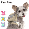 A fluffy dog wearing a beige pet backpack harness with a pink tagoon attachment.