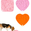 A dog is licking food from a pink silicone lick mat designed for slow feeding.