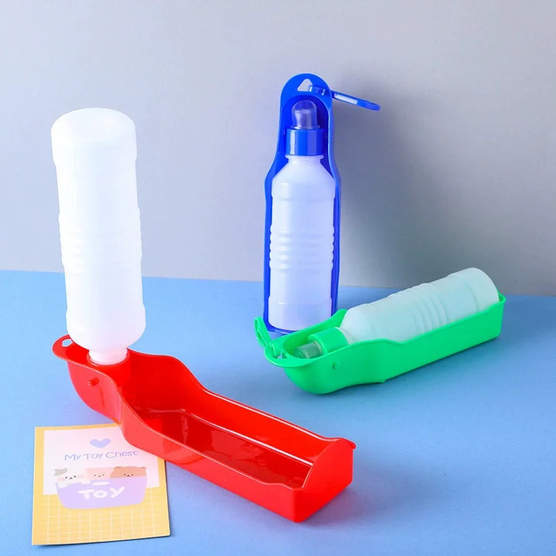 Weiße faltbare Haustierflasche mit blauer Dispenser neben einem roten Tablett und einem grünen Halter.