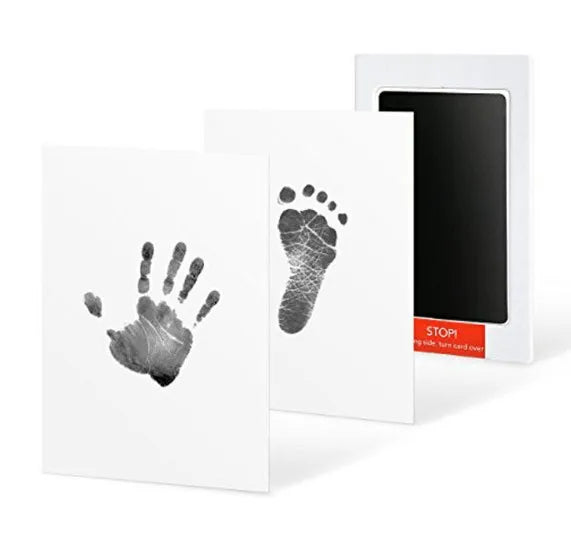 A set of black ink pet paw print and handprint cards displayed in a white frame.