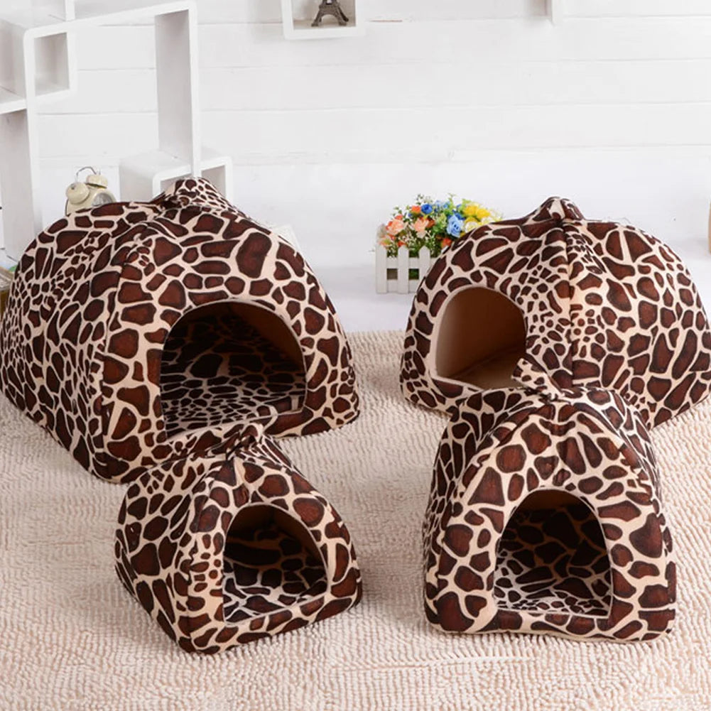 Cama para mascota de peluche con estampado de leopardo marrón y negro, sobre una superficie beige.