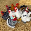 A collection of lifelike plush rooster and hen toys in various colors and textures resting on straw.