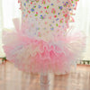 A pink floral vest for dogs and cats featuring ruffled fabric and a layered tulle skirt.