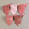 A set of five pink cotton triangle baby bibs featuring various cartoon prints and designs.