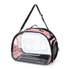 A transparent foldable pet travel carrier with a pink and black design and shoulder strap.