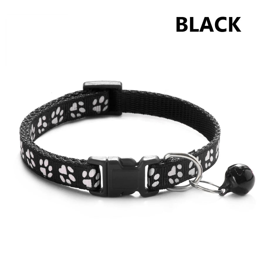 Black adjustable pet collar with a patterned strap and a small bell attached.