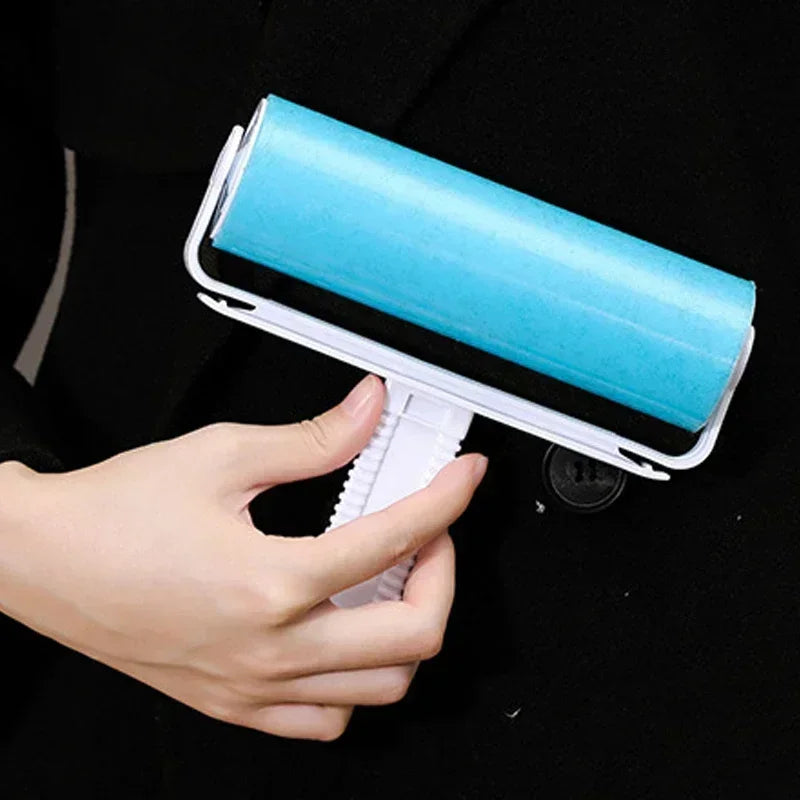 A hand holds a white lint roller with a light blue roll, demonstrating the reusable product.
