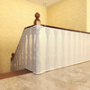 A white mesh safety barrier is installed along a wooden railing on an indoor staircase.