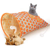 An orange and white crinkle cat tunnel with a gray cat peering out, next to a sleeping tabby kitten.