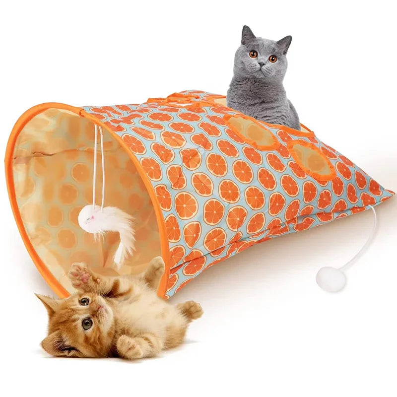 An orange and white crinkle cat tunnel with a gray cat peering out, next to a sleeping tabby kitten.