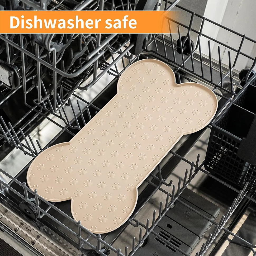 A beige anti-slip silicone pet feeding mat with a raised edge is placed inside a dishwasher rack.