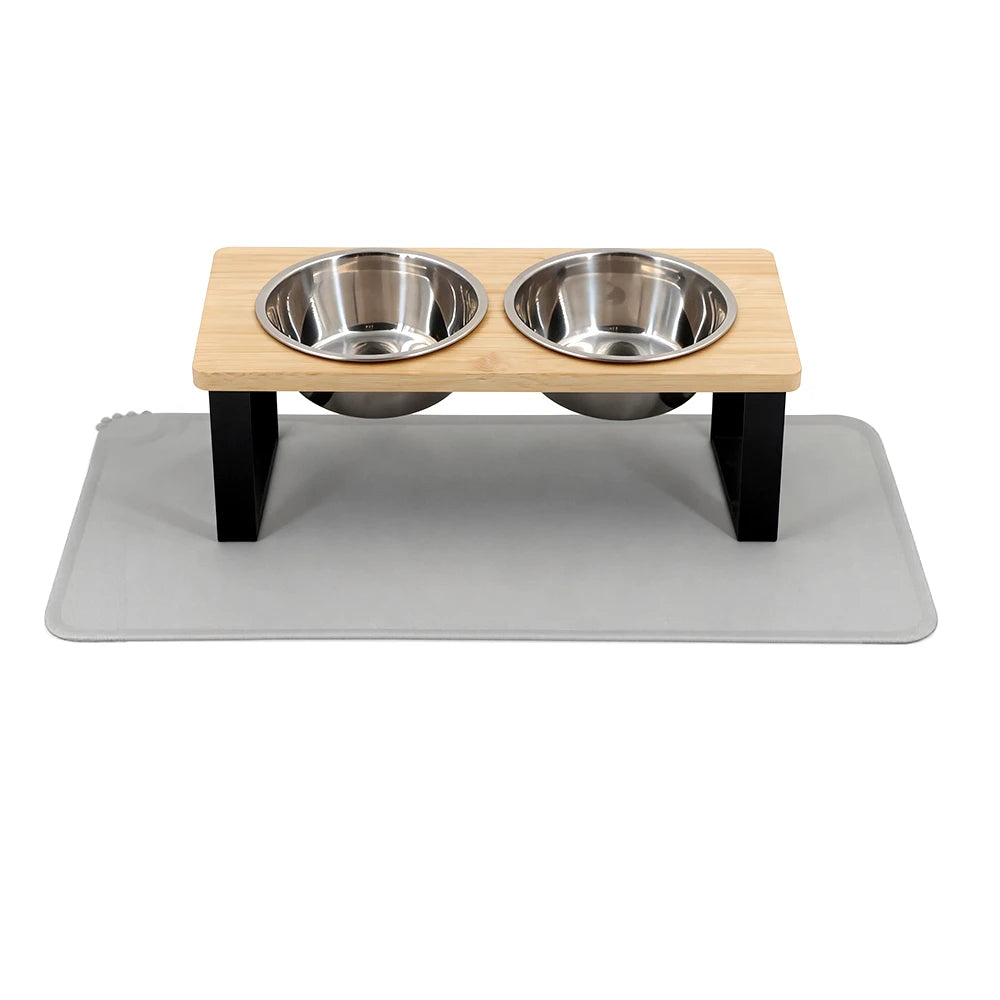 Two stainless steel bowls resting on a wooden stand within a gray food mat.