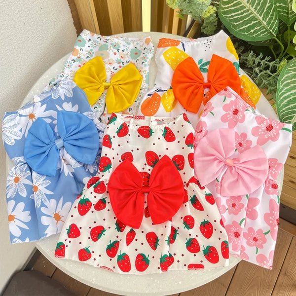 Eine Kollektion von rosa, gelben und blauen Sommerkleidern für Hündinnen mit verschiedenen Schleifenmotiven.