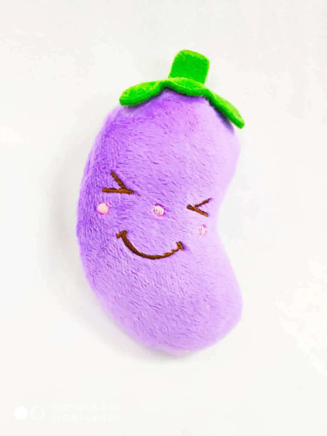 A purple bone-shaped squeaky plush dog toy with a green leaf on top.