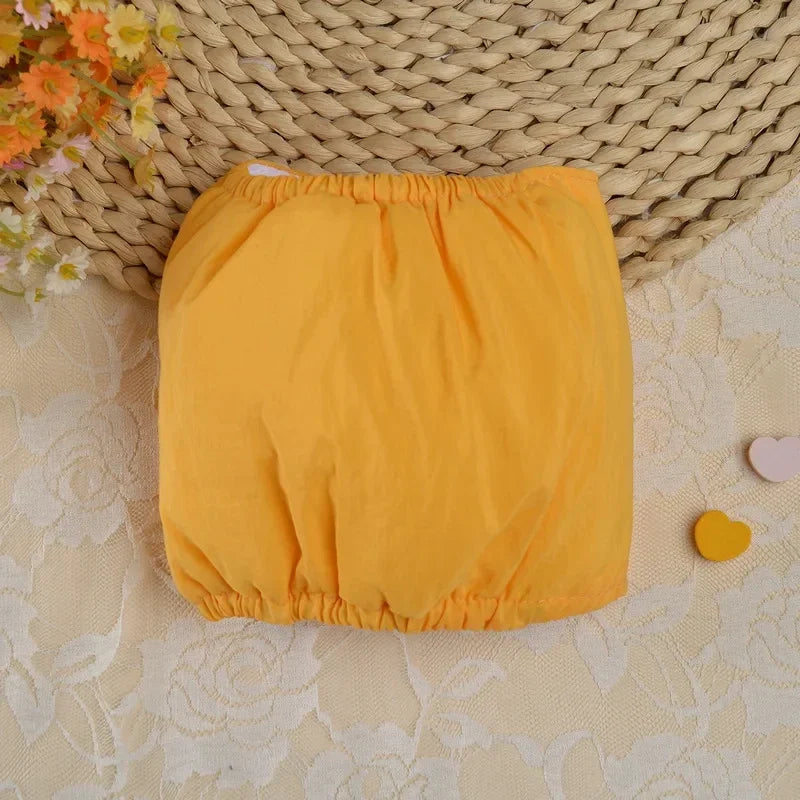Un paquet de couches réutilisables pour chien jaune vif, posé sur un tissu à motifs clairs à côté d'un tapis tissé.