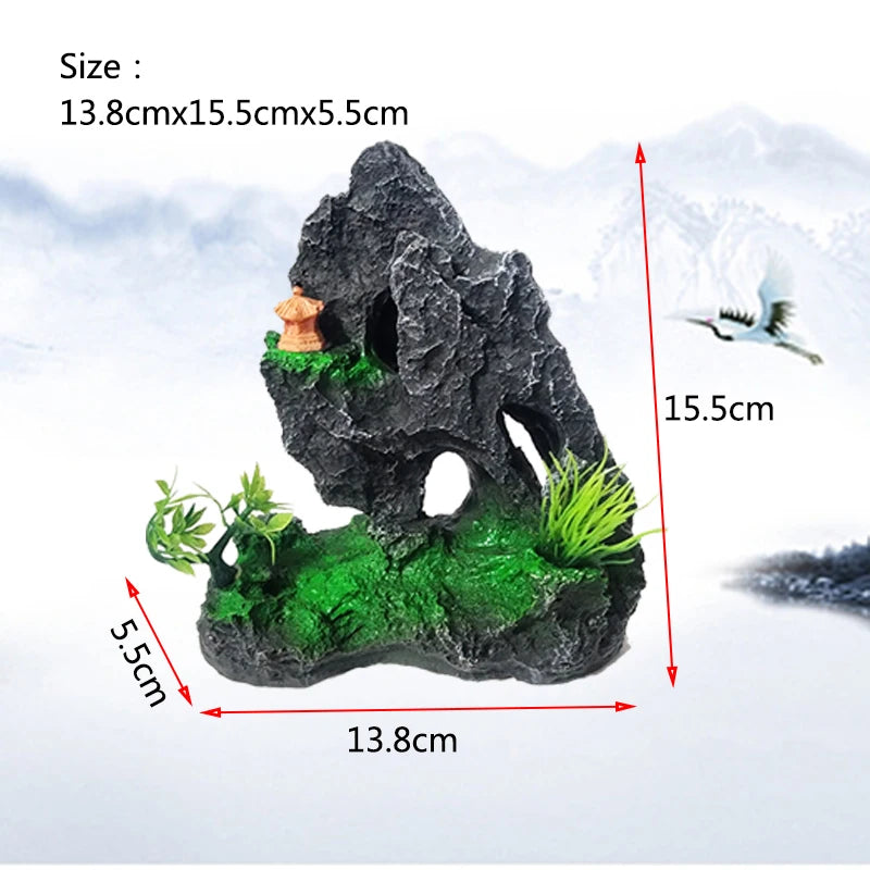 A dark gray resin rockery featuring a cave entrance, mossy green terrain, and a small orange tree on a snowy landscape.