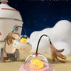 A pink automatic UFO cat teaser toy with a yellow cat head and a detachable feather wand is shown on a light surface.