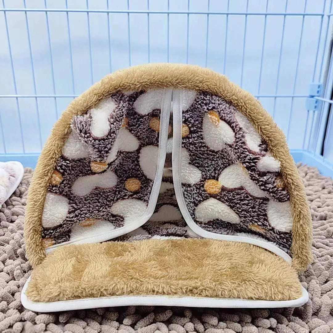 Hamaca para mascotas beige con forro estampado y ribete peludo, mostrada sobre alfombra gris.