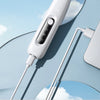 A white portable dog grooming trimmer is shown plugged into a wall outlet, with its cord extending across a light blue backgr