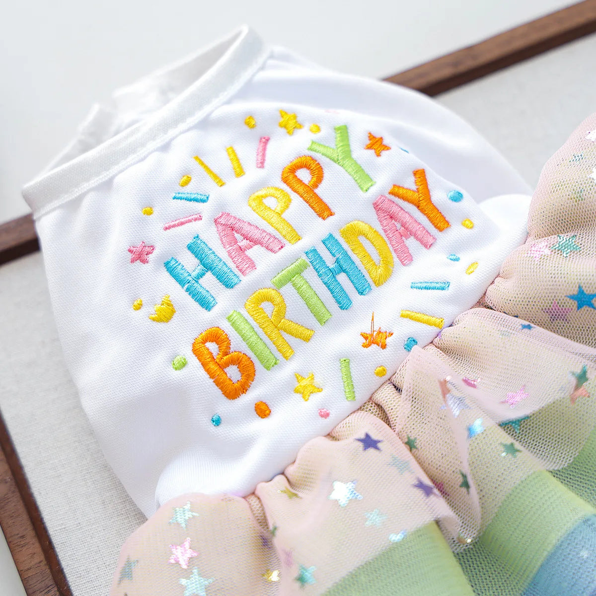 White dog birthday suit with colorful lettering and floral trim
