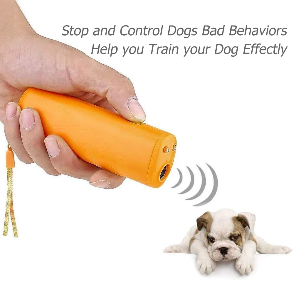 Eine Hand hält ein orangefarbenes Ultraschall-Hundbell-Aversiv, mit einem Welpen in der Nähe.