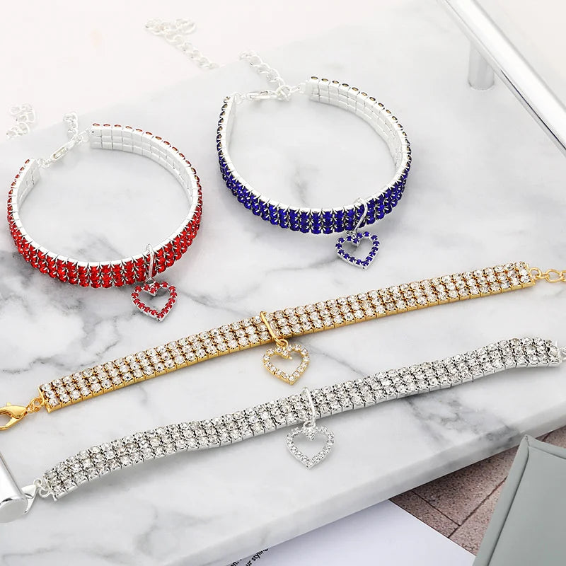 A display of elegant rhinestone collars for dogs and cats in red, blue, and silver tones.