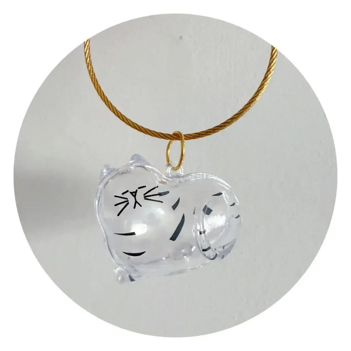 A clear silicone pet hair storage keychain with a cat face design attached to a gold-colored cord.