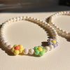 A set of pastel floral beaded necklaces featuring yellow, pink, and purple beads.