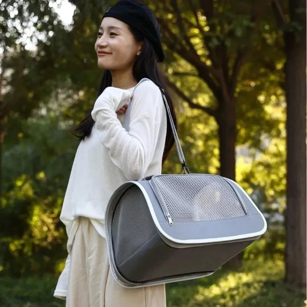 A woman is holding a gray breathable pet carrier bag for cats and small dogs outdoors.