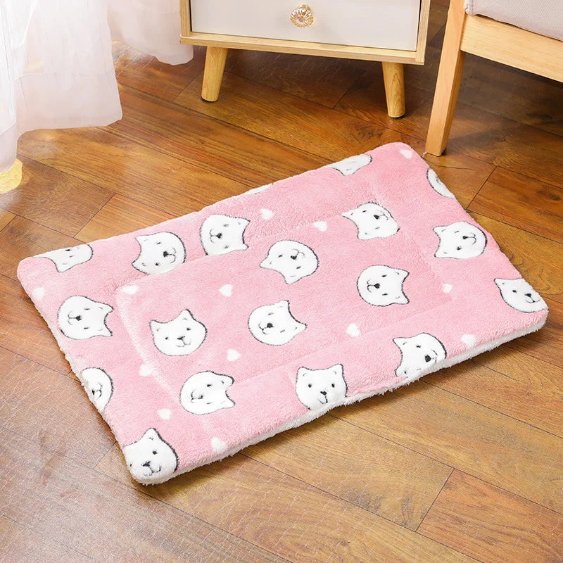 Tapis de lit pour animal en peluche rose avec des motifs embroidered de chats blancs, posé sur un plancher en bois.