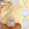 Clear silicone hamster figurine keychain with pink accents hanging from a leather bag