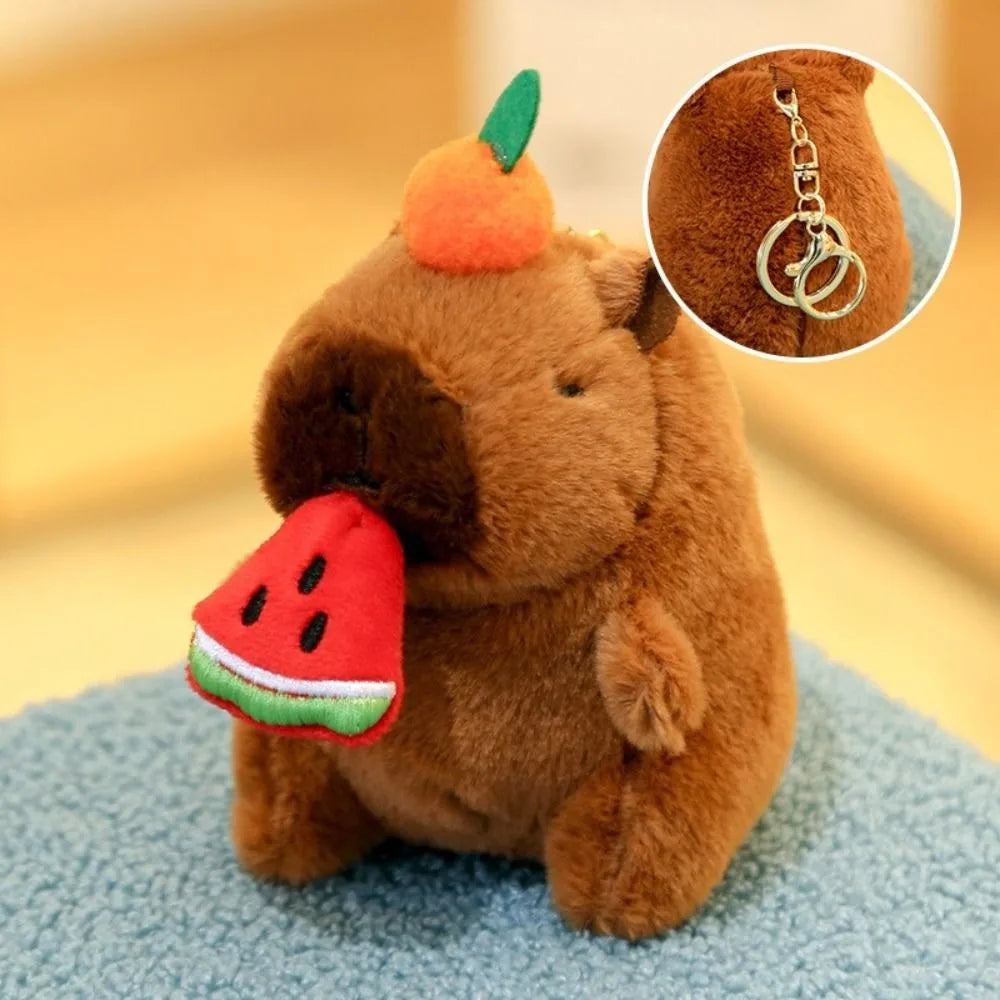 Braune Capybara-Plüschpuppe mit einer orangen Frucht auf dem Kopf und einem Wassermelonenstück dran.