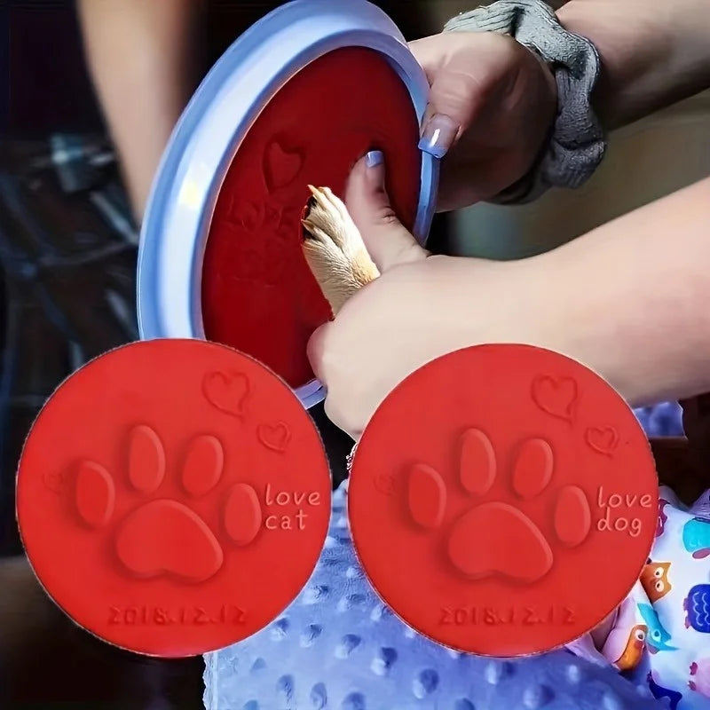 Hands are pressing red clay paw prints into a clear mold to create pet memory ornaments.