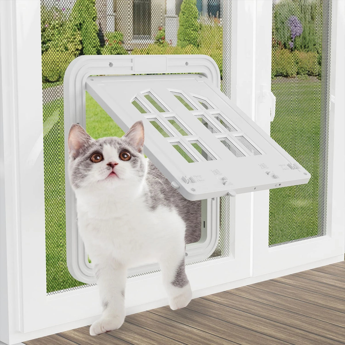 A domestic cat stands in front of a white window with a magnetic mesh screen door and a self-closing pet flap installed.