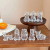 A collection of clear glass pet hair storage keychains shaped like various dog breeds displayed on a wooden stand.