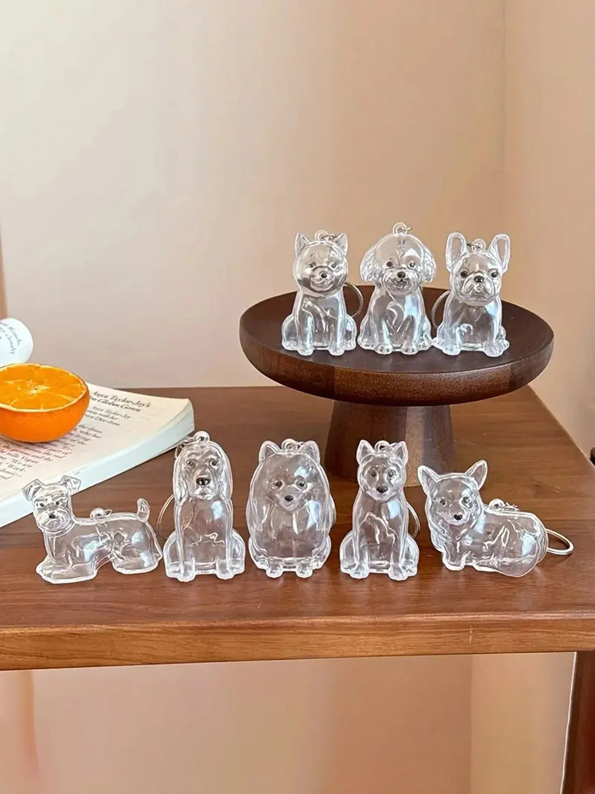 A collection of clear glass pet hair storage keychains shaped like various dog breeds displayed on a wooden stand.