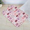 A pink patterned washable pet training mat featuring cute cat faces for dogs on a light wooden floor.