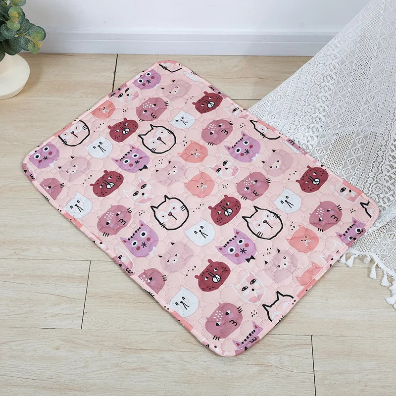 A pink patterned washable pet training mat featuring cute cat faces for dogs on a light wooden floor.