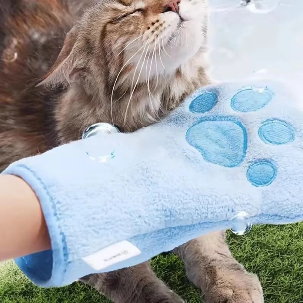 A cat is using a light blue quick-dry pet bathing towel glove with paw prints on its paw.