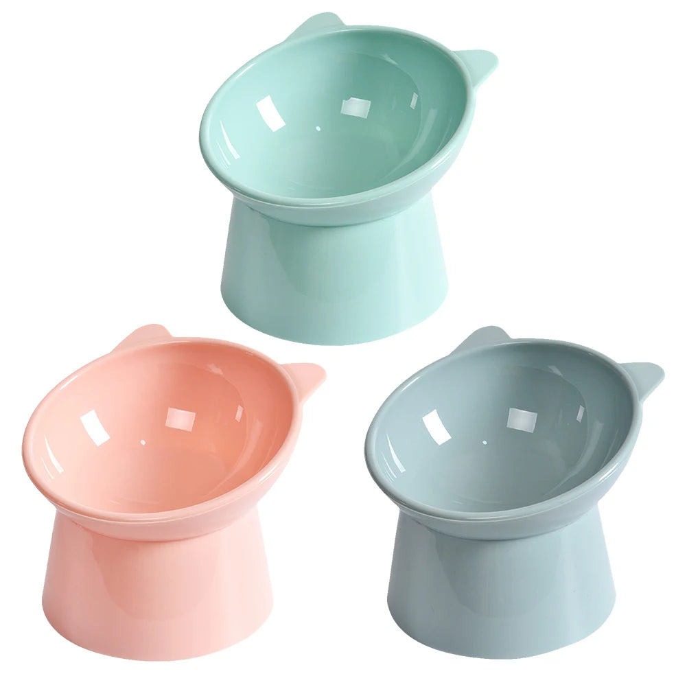 A set of two ergonomic tilted cat food bowls in light mint green and soft pink with non-slip bases.