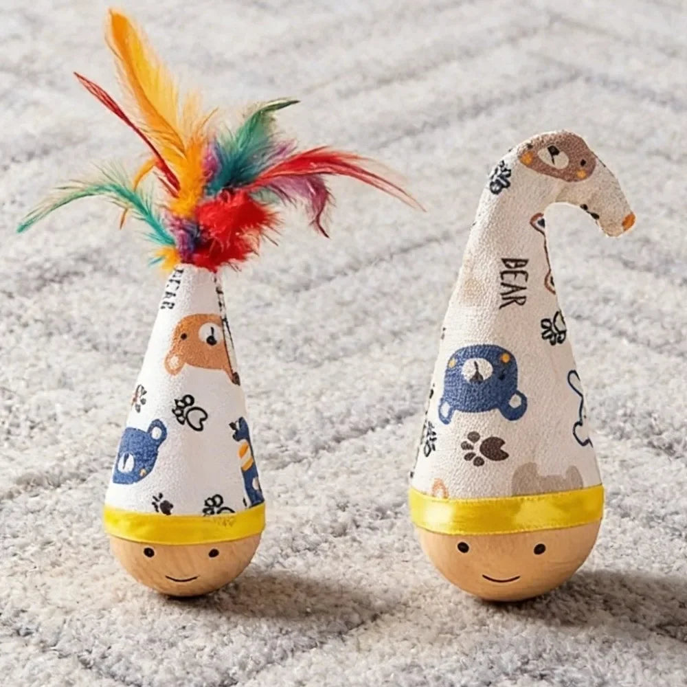 A knitted toy shaped like a bear with colorful feathers, sitting on a textured surface.